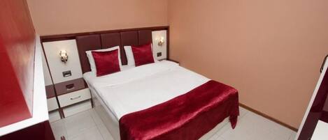 Habitación de hotel con cama, mesitas de noche y una manta roja.