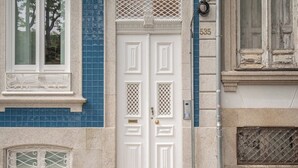 Una puerta doble blanca con paneles decorativos, una ventana con reja de metal y el número '535' en la pared.