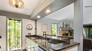 A modern kitchen with a large island, built-in appliances, and a stone fireplace. - Wastin' Away - Margaritaville, Just Steps to the Pool! (Osage Beach)