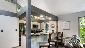 A modern kitchen with a central island, built-in appliances, and a dining area with a bench and chairs. - Wastin' Away - Margaritaville, Just Steps to the Pool! (Osage Beach)