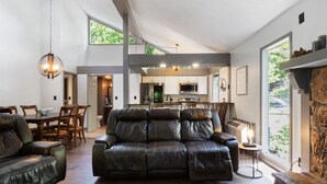 A spacious living room with a leather sofa, dining area, and a kitchen with large windows. - Wastin' Away - Margaritaville, Just Steps to the Pool! (Osage Beach)