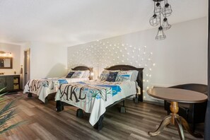 Ein Schlafzimmer mit zwei Betten, einem Nachttisch, einem Sessel und einer Pendelleuchte.