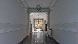 A hallway with marble floors and white walls, leading to a bright room with a large window. - Azure Loft by Wonderful Italy (Torino)