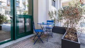 A balcony with a green door, a blue table and chairs, and a potted plant. - Pink Loft by Wonderful Italy (Torino)