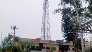 A hotel with a modern design, featuring a prominent tower in the background. - lvy Hotel And Restaurant (Mukerian)