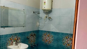 A bathroom with a white pedestal sink, a mirror, and a water heater mounted on the wall. - lvy Hotel And Restaurant (Mukerian)