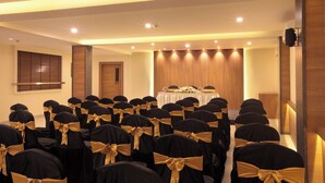 Ein Konferenzraum mit Reihen von Stühlen, einem Tisch mit Blumenarrangements und Holzvertäfelung an den Wänden.