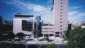 A modern building with a prominent tower and a flat facade with large windows. - Howard Civil Service International House (Taipei)