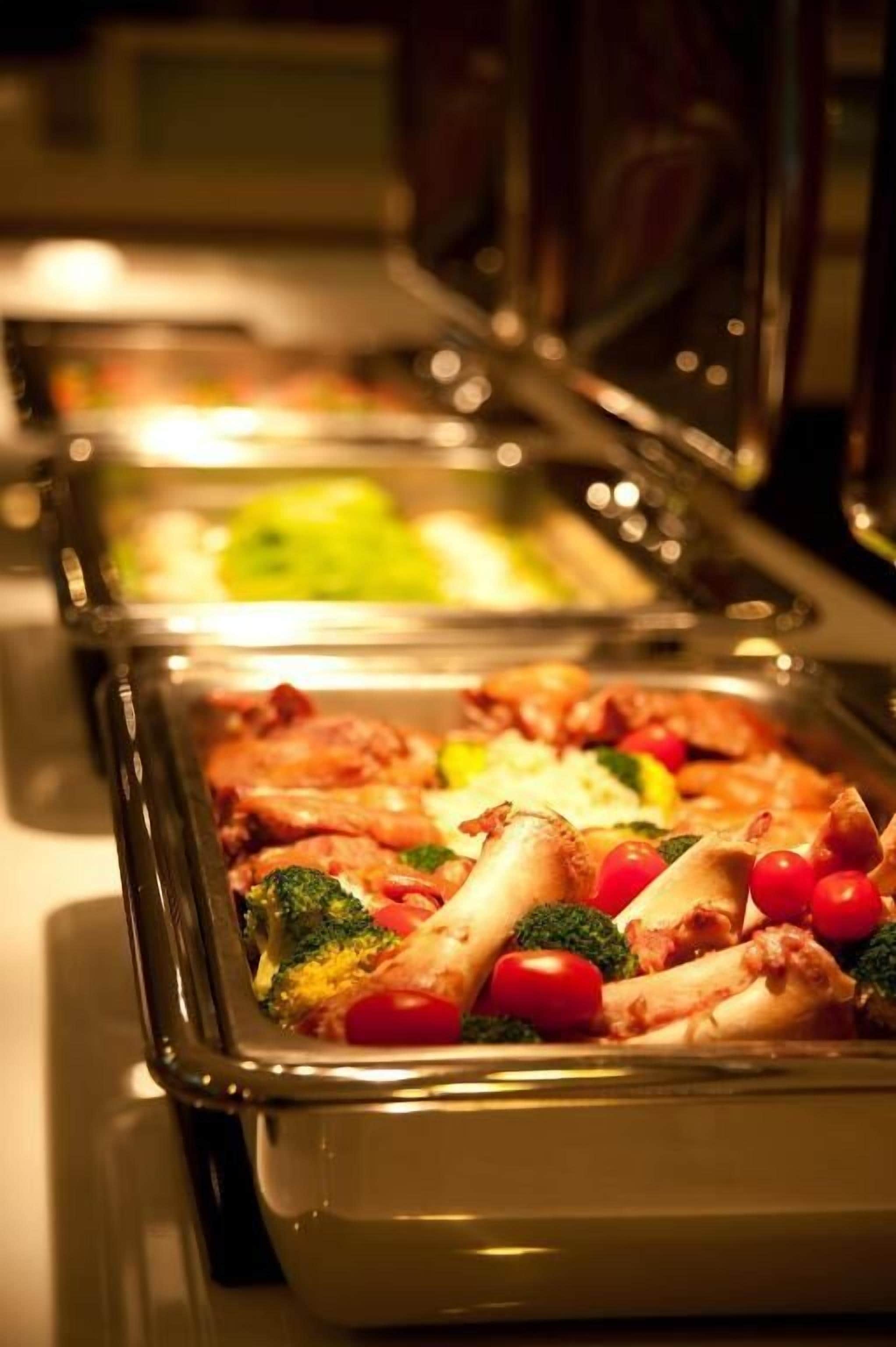 Ein reichhaltiges Buffet mit verschiedenen Speisen, darunter Pasta, Gemüse und Fleisch.
