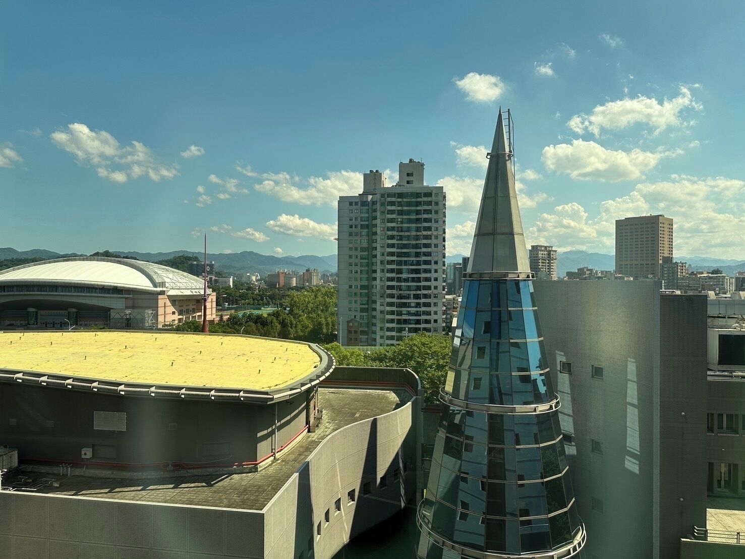 Un estadio con un amplio campo abierto, un edificio moderno de vidrio y una alta aguja.