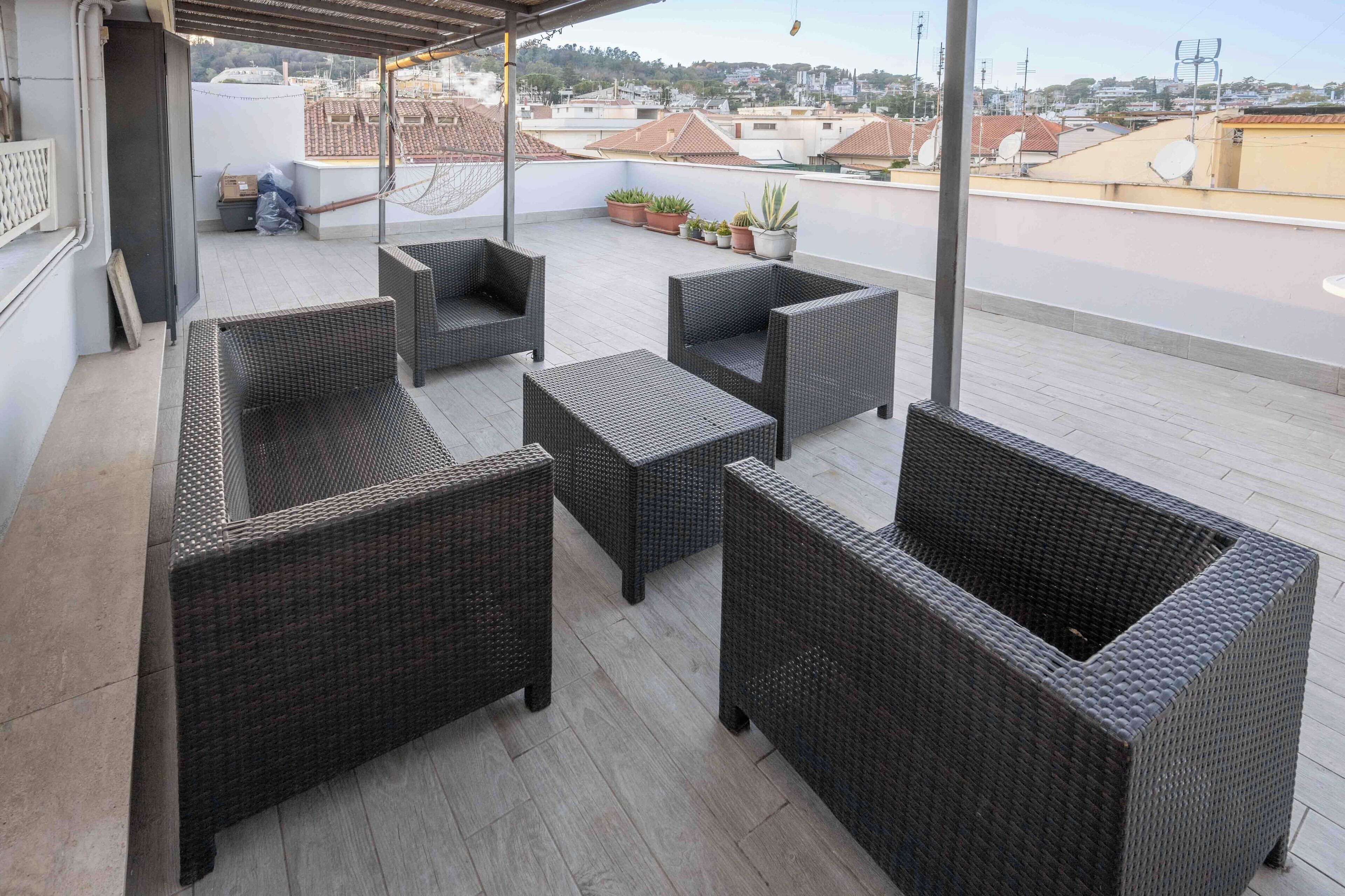 Une terrasse sur le toit, aménagée avec des meubles en osier, des plantes en pot et offrant une vue sur le paysage urbain.