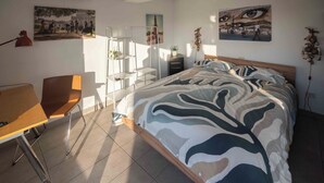 A bedroom with a bed, a desk, and a chair. There are paintings on the walls and a ladder. - Farnesina Rooftop Terrace (Roma)