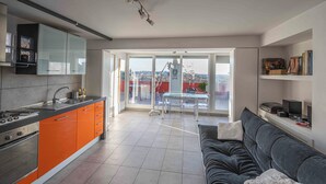 A modern kitchen with orange cabinets, a black countertop, and a large window. - Farnesina Rooftop Terrace (Roma)