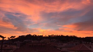 A sunset over a residential area with buildings and trees. - Farnesina Rooftop Terrace (Roma)