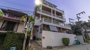 A multi-story residential building with balconies, a white exterior, and a visible power line. - Sea View Near Beach  MuayThai C230 (Rawai)