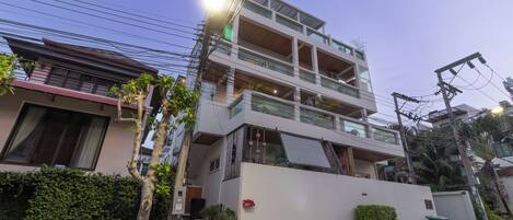 A multi-story residential building with balconies, a white exterior, and a visible power line.