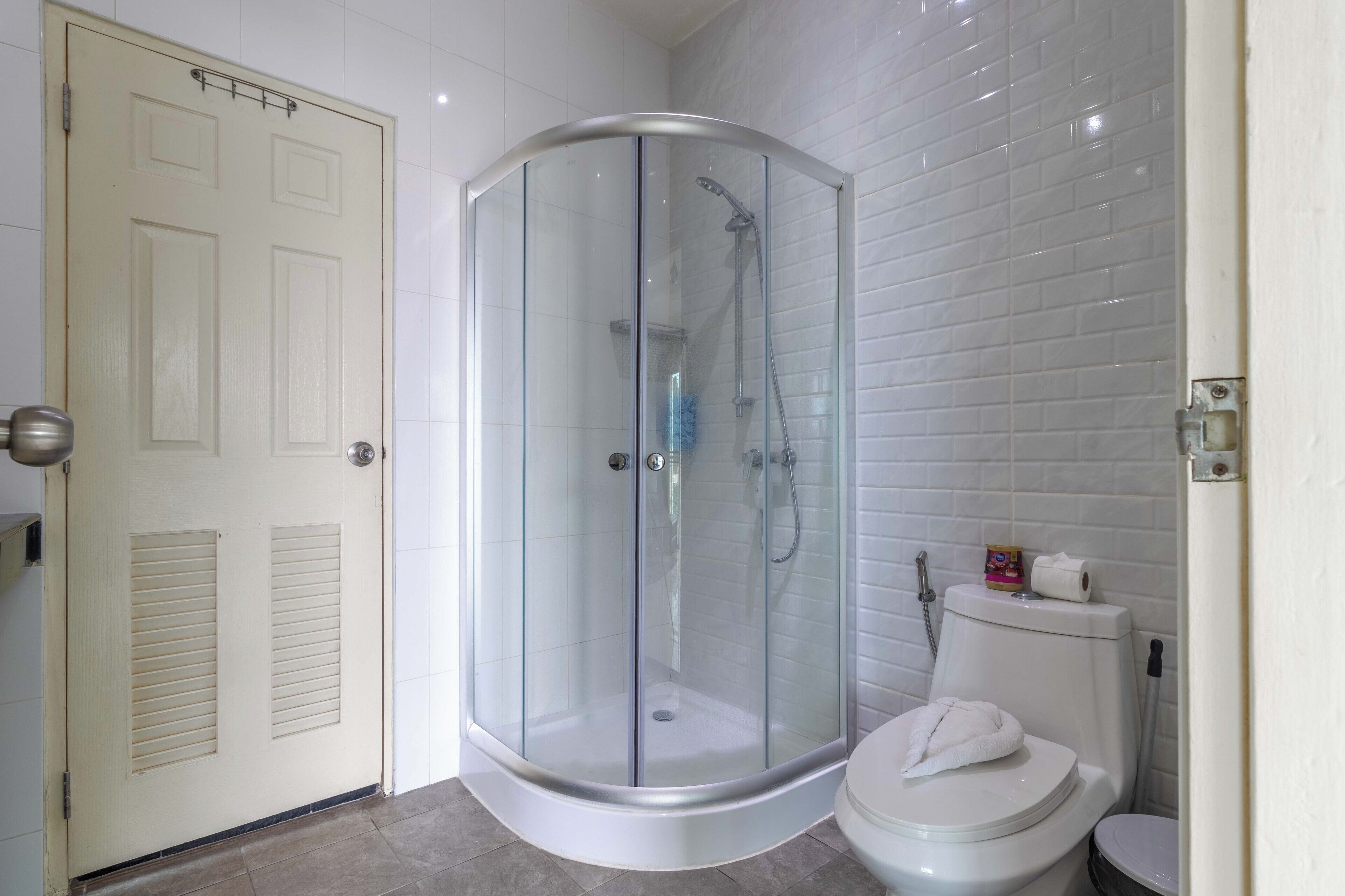 Un baño en esquina con ducha de vidrio, inodoro y puerta.