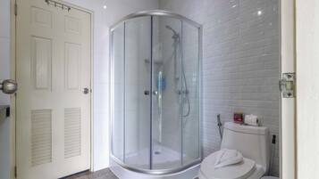 Un baño en esquina con ducha de vidrio, inodoro y puerta.