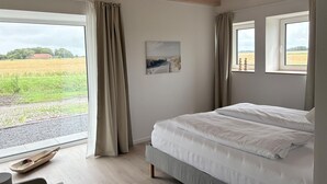 A bedroom with a bed, a window, and a view of a field.