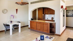 Una cocina moderna con armarios de madera, una encimera blanca y una zona de comedor con una mesa y sillas.