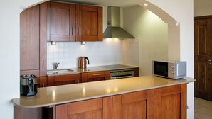 Una cocina con armarios de madera, un tostador de acero inoxidable, una tetera y un microondas sobre la encimera.