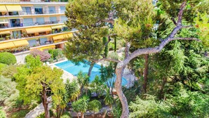 Un hôtel à plusieurs étages doté de balcons, d’une piscine et d’une végétation luxuriante.