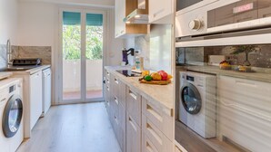 Une cuisine moderne dotée d’appareils électroménagers intégrés, d’un lave-linge et d’une grande fenêtre offrant une belle vue.