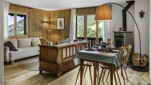 A cozy room with a wooden interior, a sofa, a dining table set for two, and a fireplace. - Val d'Illiez, 6 pers • Balcony & view - parking (Val-d`Illiez)