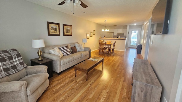 A spacious living room with a sofa, coffee table, and a dining area with chairs and a table.