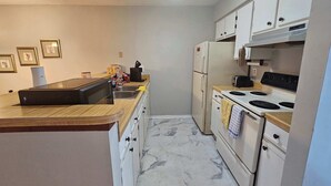A compact kitchen with white cabinets, a built-in stove, and a microwave.