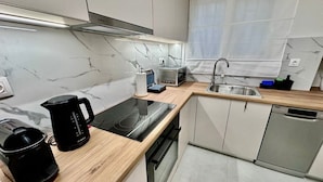 Una cucina moderna con piano cottura a induzione nero, una macchina da caffè Bosch, un forno a microonde e una lavastoviglie.