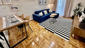 Un soggiorno moderno con un divano blu, un tavolo da pranzo per quattro persone e un tappeto a righe bianco e nero.