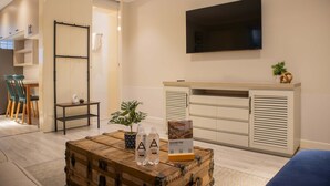 Une chambre d’hôtel moderne avec une commode en bois, un téléviseur à écran plat, une plante et un panneau d’information sur le Pérou.