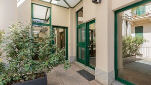 Una entrada de edificio con puertas verdes y un corredor cubierto.