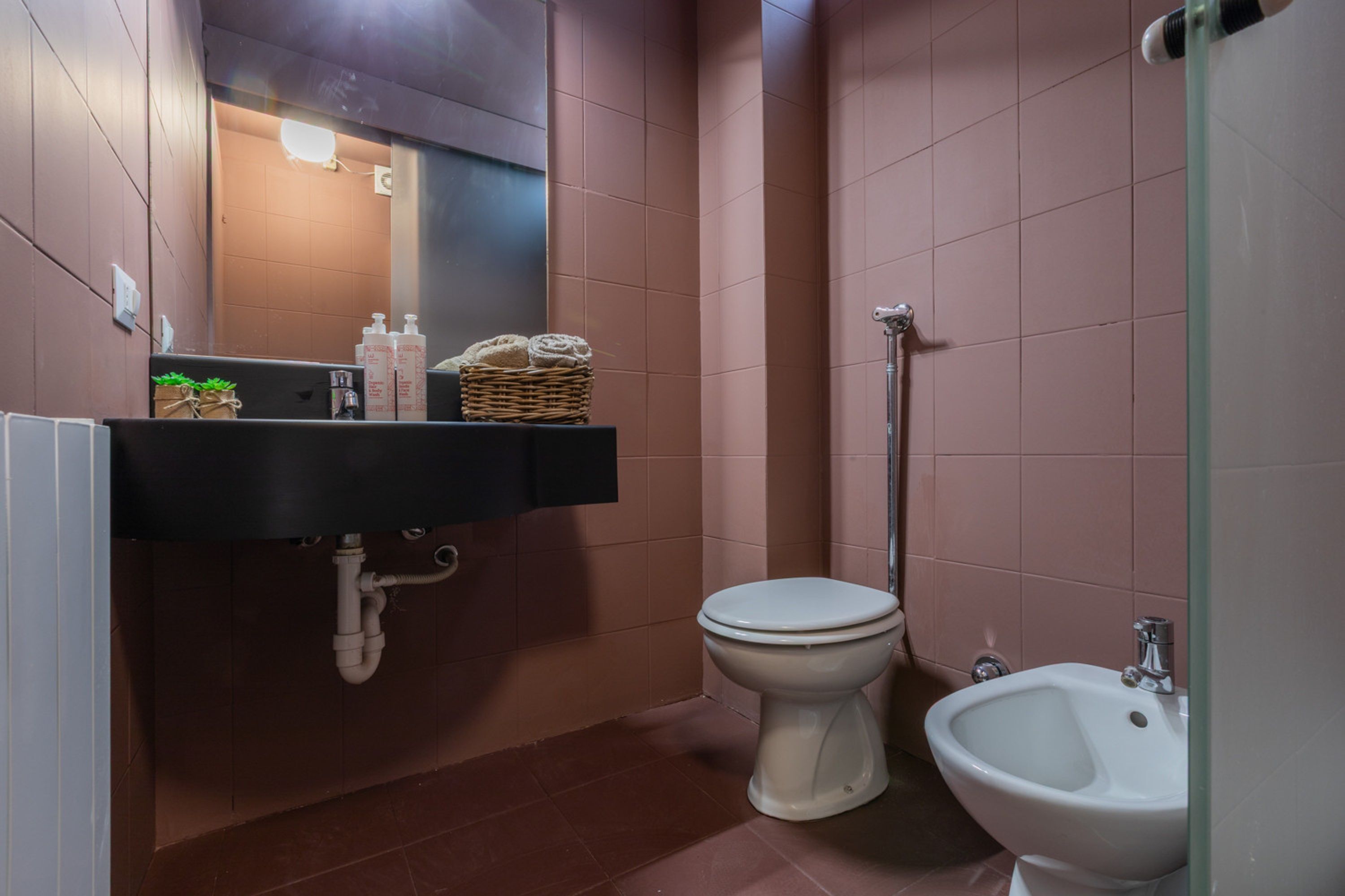 A bathroom with a black sink, white toilet, and bidet.