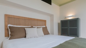 A neatly made bed with a wooden headboard, a green throw blanket, and two pillows. - Green Loft by Wonderful Italy (Turin)