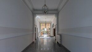 A hallway with a polished granite floor, white walls, and a chandelier. - Green Loft by Wonderful Italy (Turin)