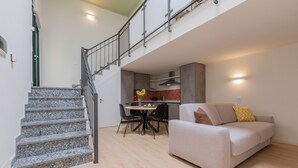 A modern apartment with a staircase, a dining area, and a living room with a sofa. - Green Loft by Wonderful Italy (Turin)