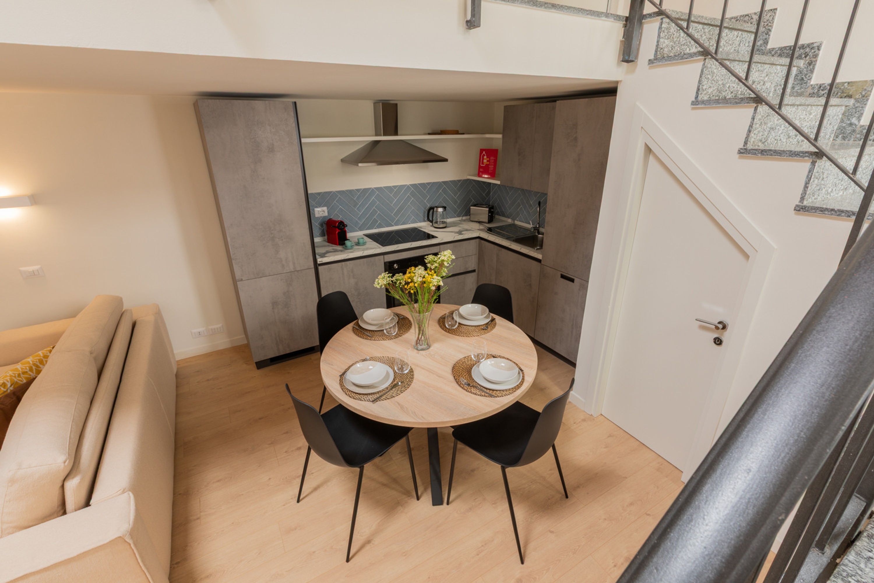 Cocina compacta con comedor, sofá y escalera.
