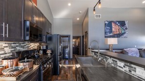 A modern kitchen with dark cabinetry, stainless steel appliances, and a large island with a sink. - Epic Mountain View Dark Skies Retreat with 2 Living Spaces, Perfect for Couples & Families (Silver Cliff)