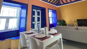 Un espace repas doté d’un plafond haut, de murs bleus et jaunes, et d’un lustre.