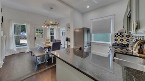 A modern kitchen with a central island, stainless steel appliances, and a dining area with a table and chairs. - Stylish 2BR Inman Park Flat w/ Porch & Fireplace (Atlanta)
