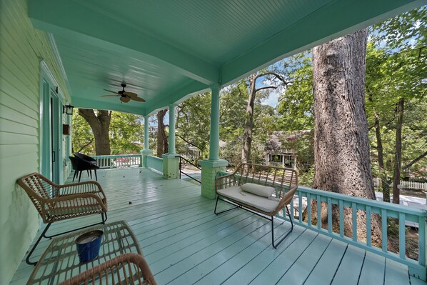 A covered porch with wicker furniture, a ceiling fan, and a view of trees. - Stylish 2BR Inman Park Flat w/ Porch & Fireplace (Atlanta)