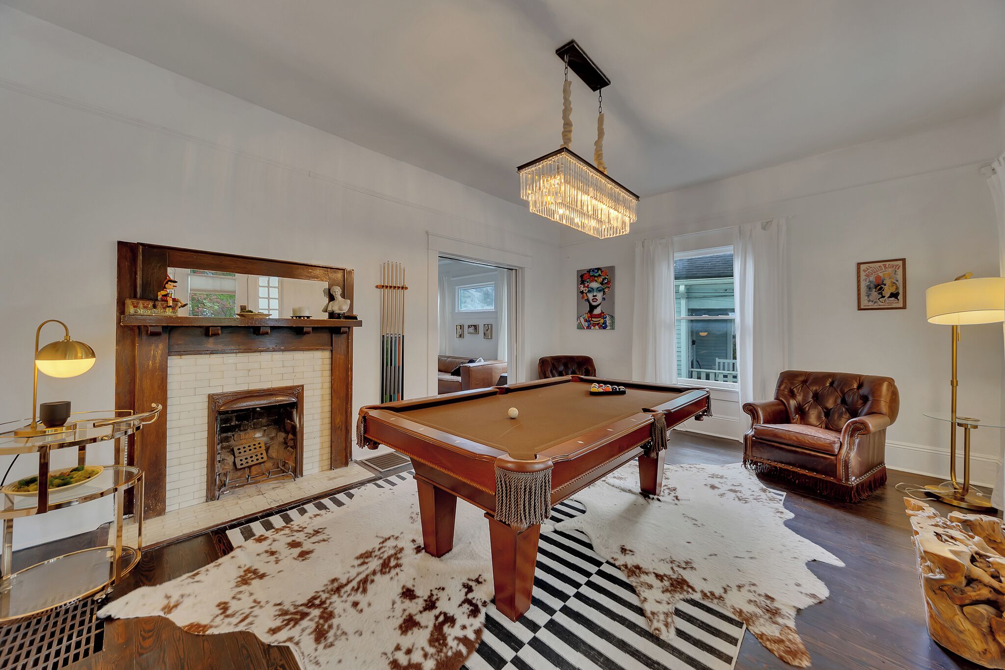 A spacious living room with a pool table, leather armchair, and a fireplace.