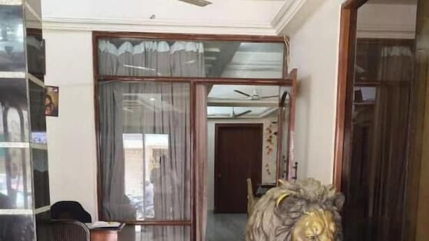 A room with a marble floor, a ceiling fan, a large mirror, and a statue of a lion. - Hotel Dwarika Inn (Rajkot)