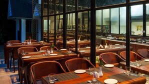 Un restaurante con techo de vidrio moderno, mesas y sillas de madera.