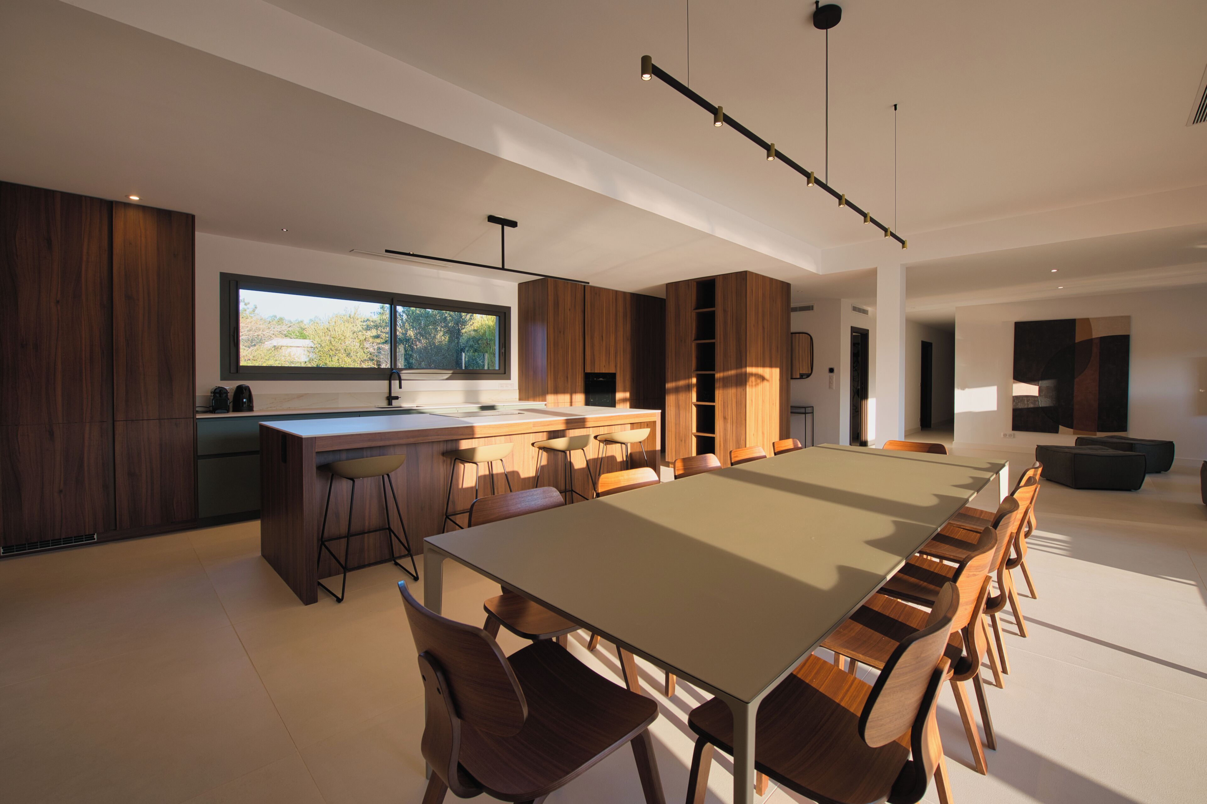 Una cucina moderna con una grande isola, mobili in legno e un'area pranzo con un tavolo lungo e sedie.