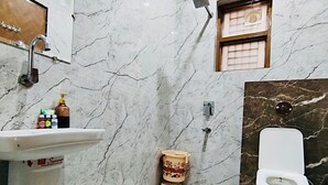 Ein Badezimmer mit Marmorwand, Waschbecken, Toilette und kleinem Fenster.