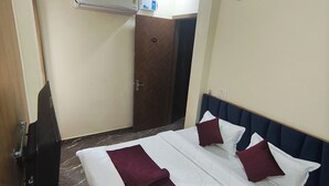Ein Hotelzimmer mit Bett, Deckenventilator, Klimaanlage und einer Tür.