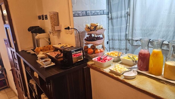 A breakfast buffet with various fruits, juices, and a coffee machine. - Hostal El Auqui (Cusco)